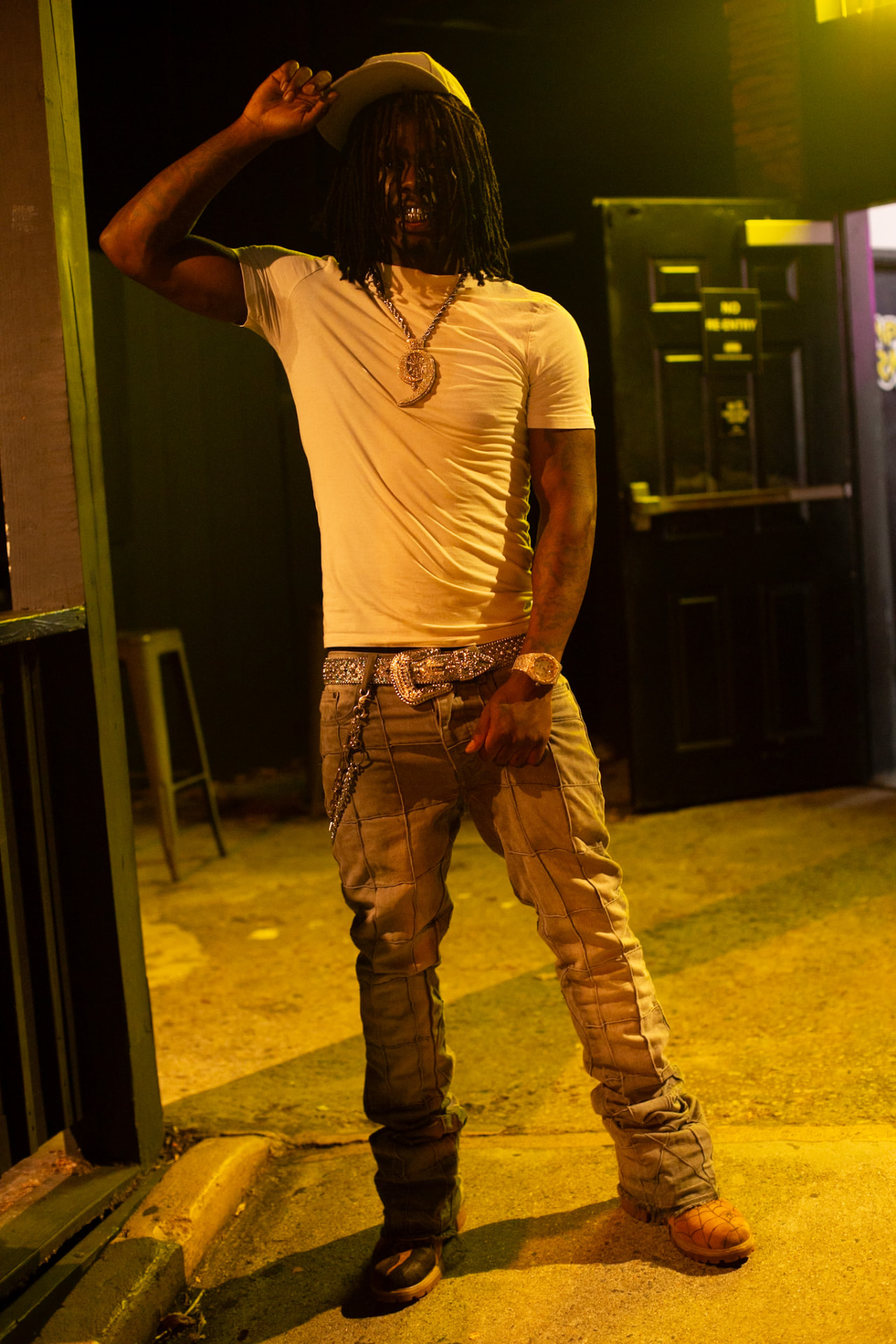 Night event portrait — white tee, chains and stacked denim under street light
