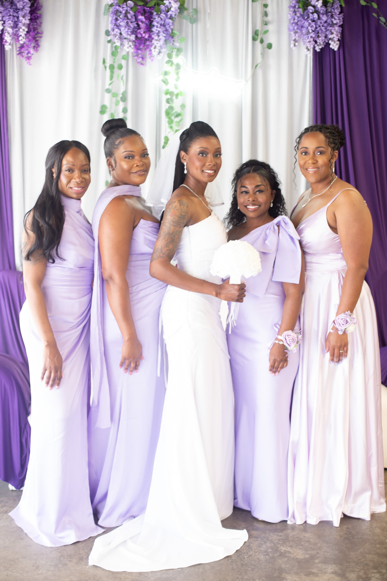 Wedding — the bride and her bridesmaids smiling in lilac and white