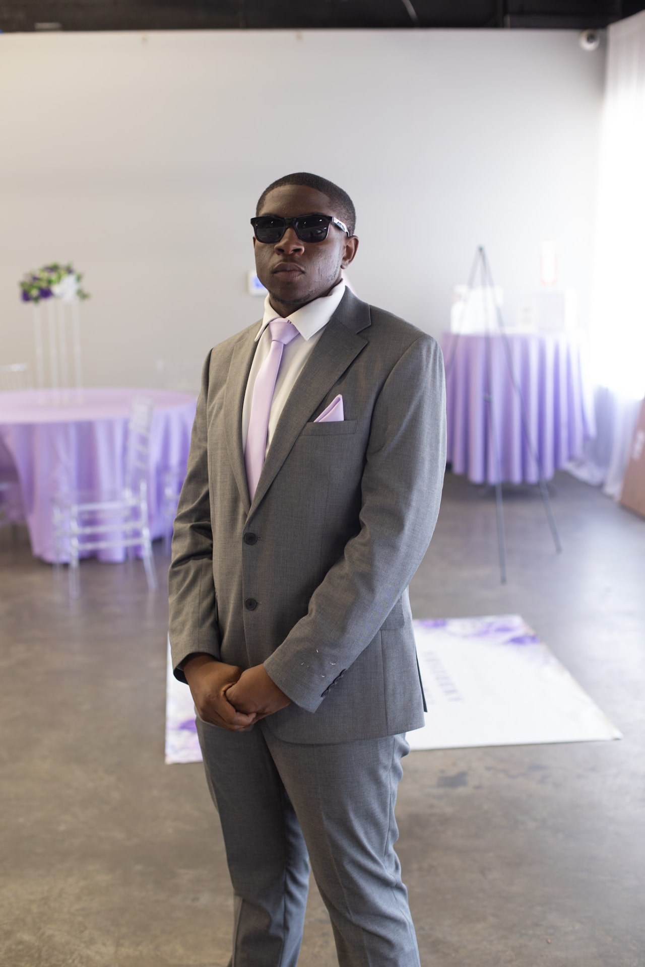 Wedding — groomsman in shades with hands folded in front of the ceremony set