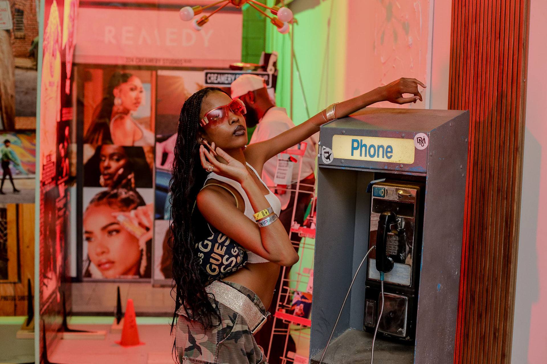 Model editorial — shades and braids at the payphone, pop-art set