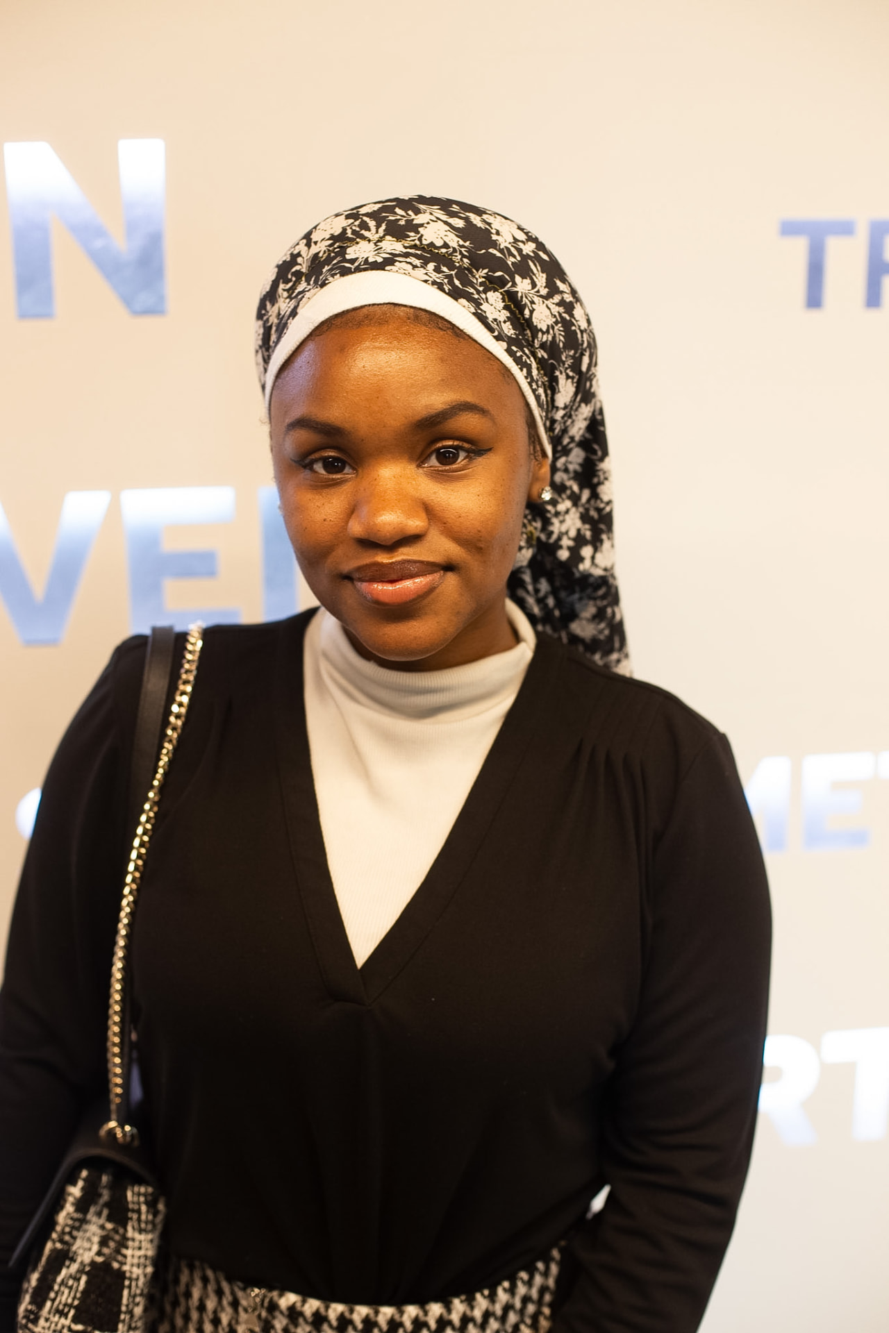 Portrait — floral headwrap and white turtleneck on the step-and-repeat