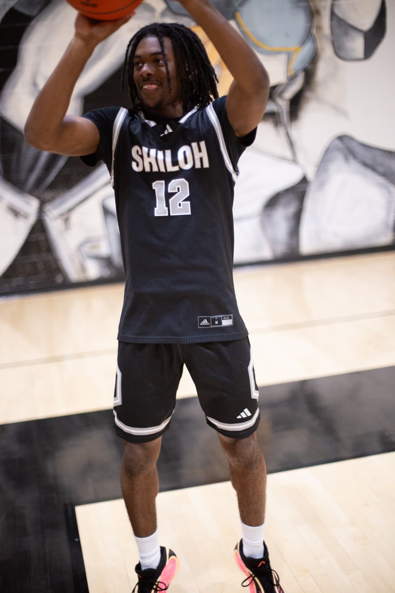Sports portrait — number 12 with the ball, all smiles on the home floor