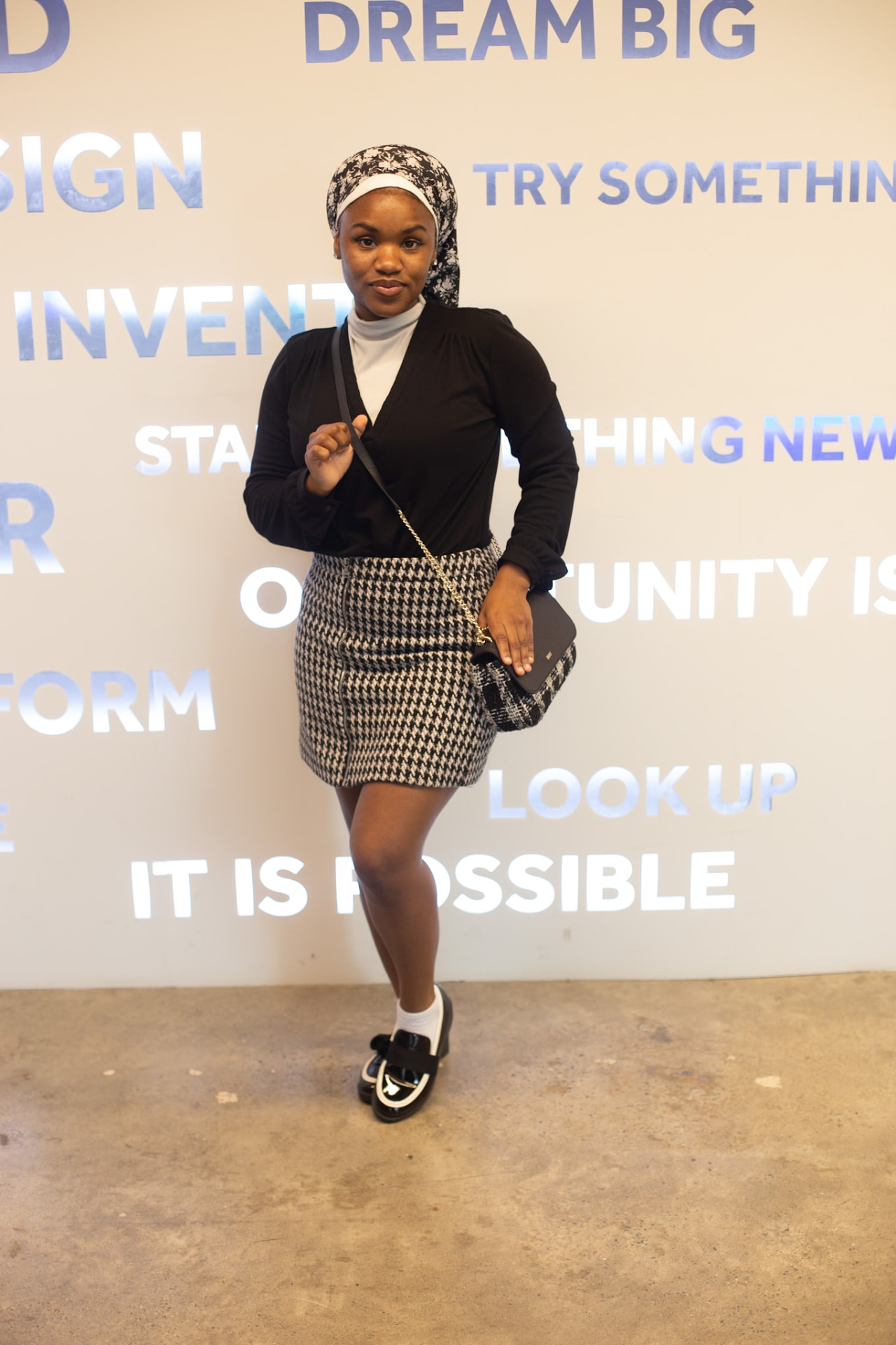 Model editorial — black blouse and houndstooth mini in motion