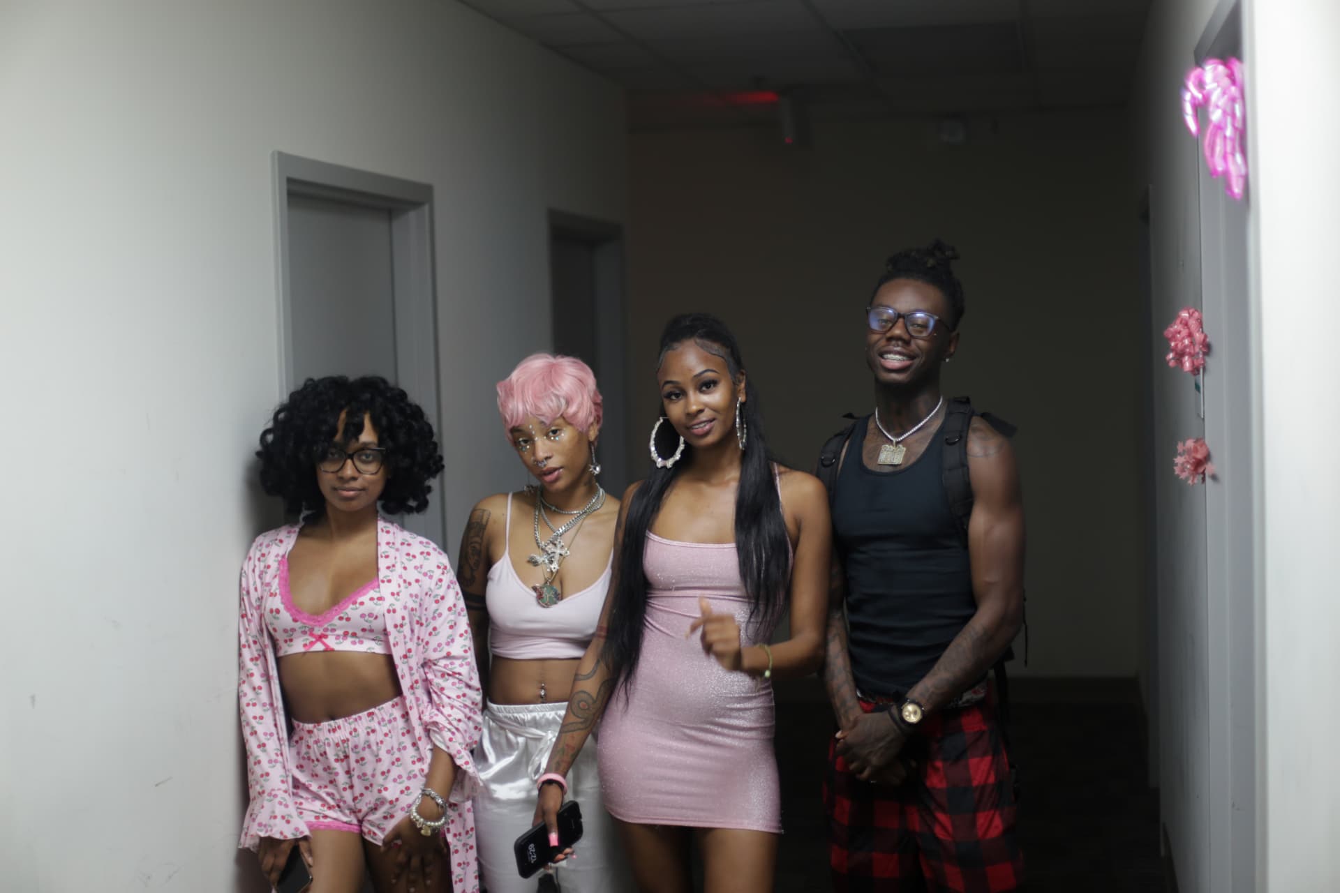 Pink-themed party — four guests lined up in the hallway