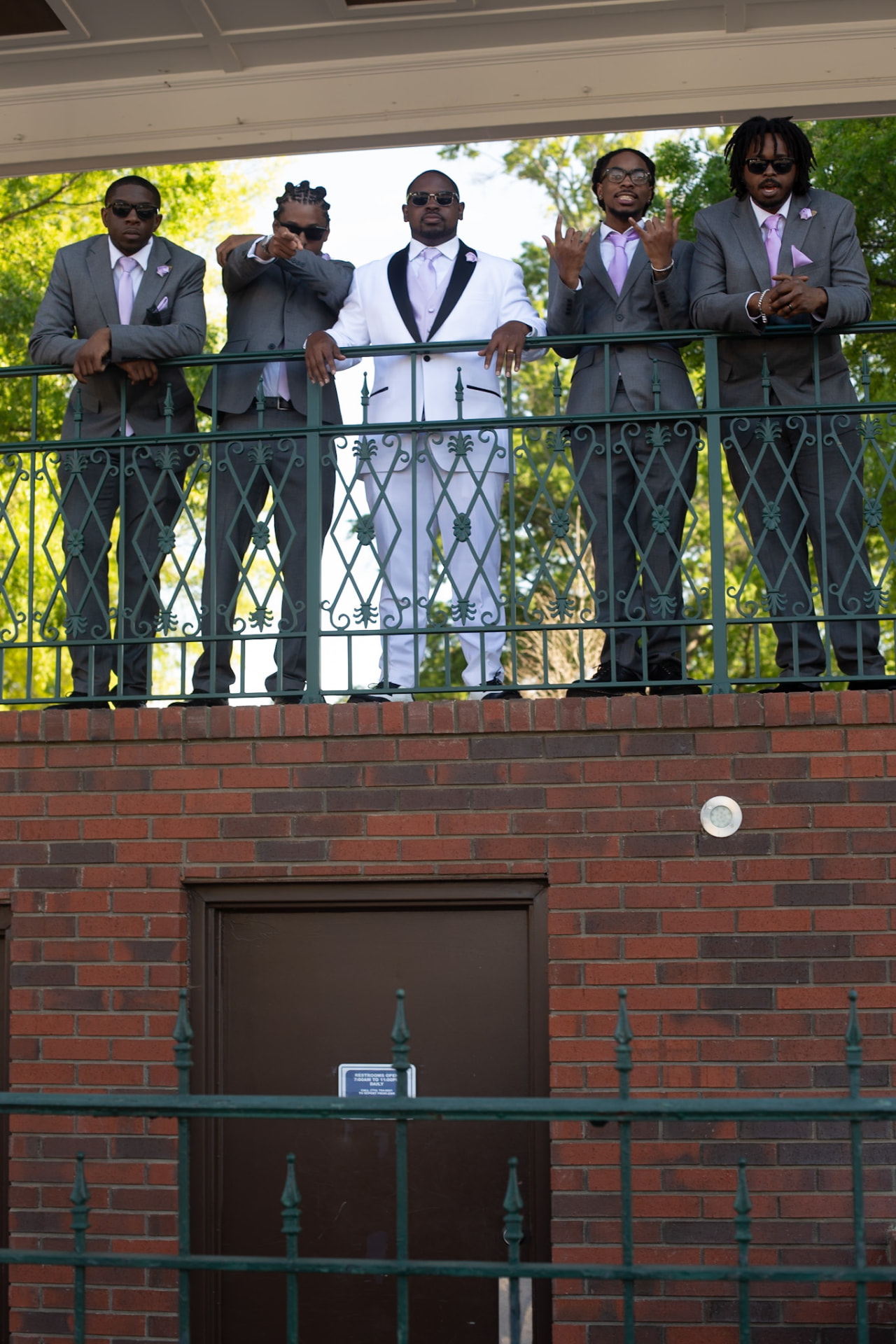 Wedding — groom and groomsmen leaning on the balcony rail, throwing up the signs