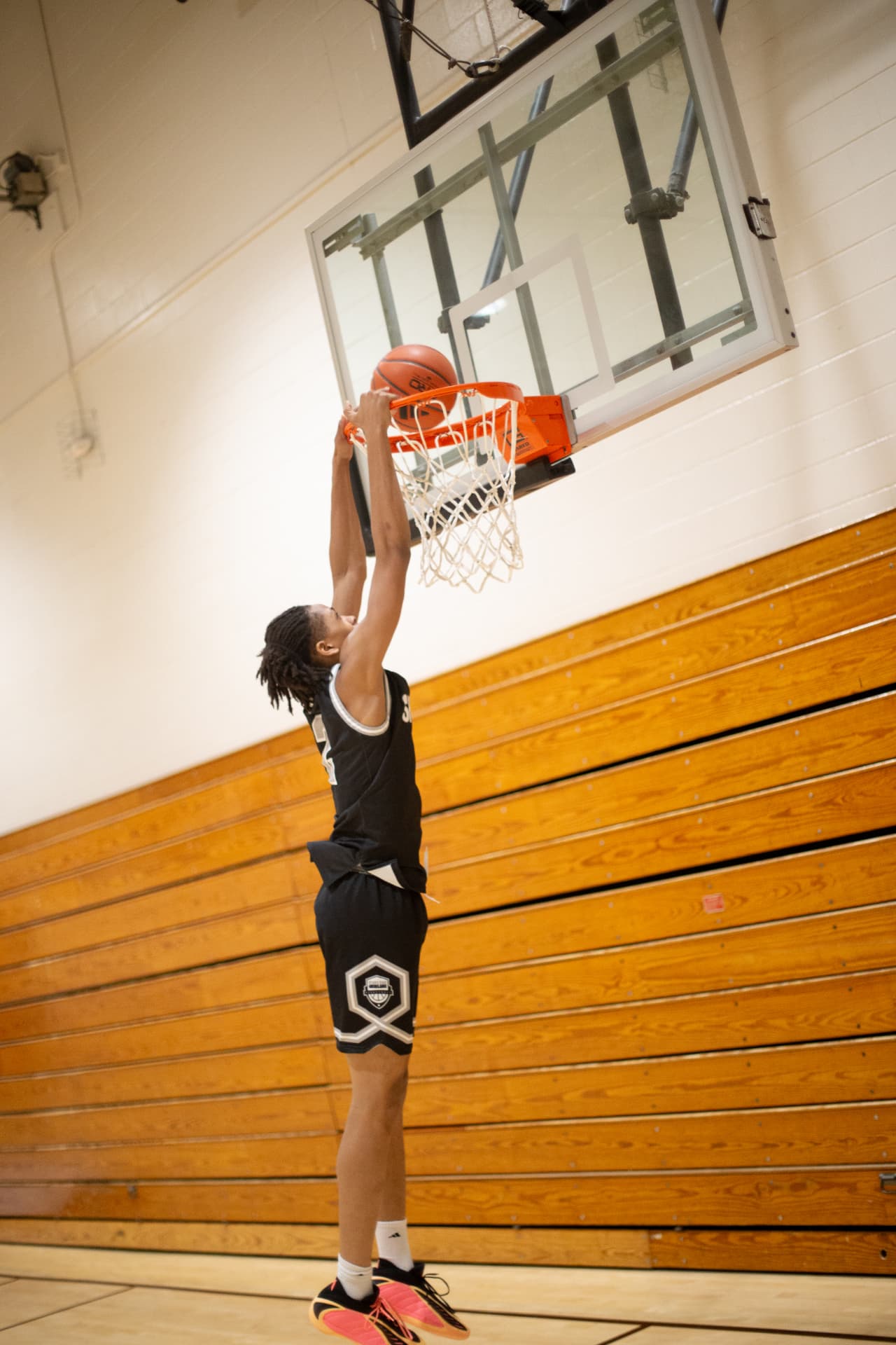 Sports action — two-hand dunk over the rim, mid-air in the gym