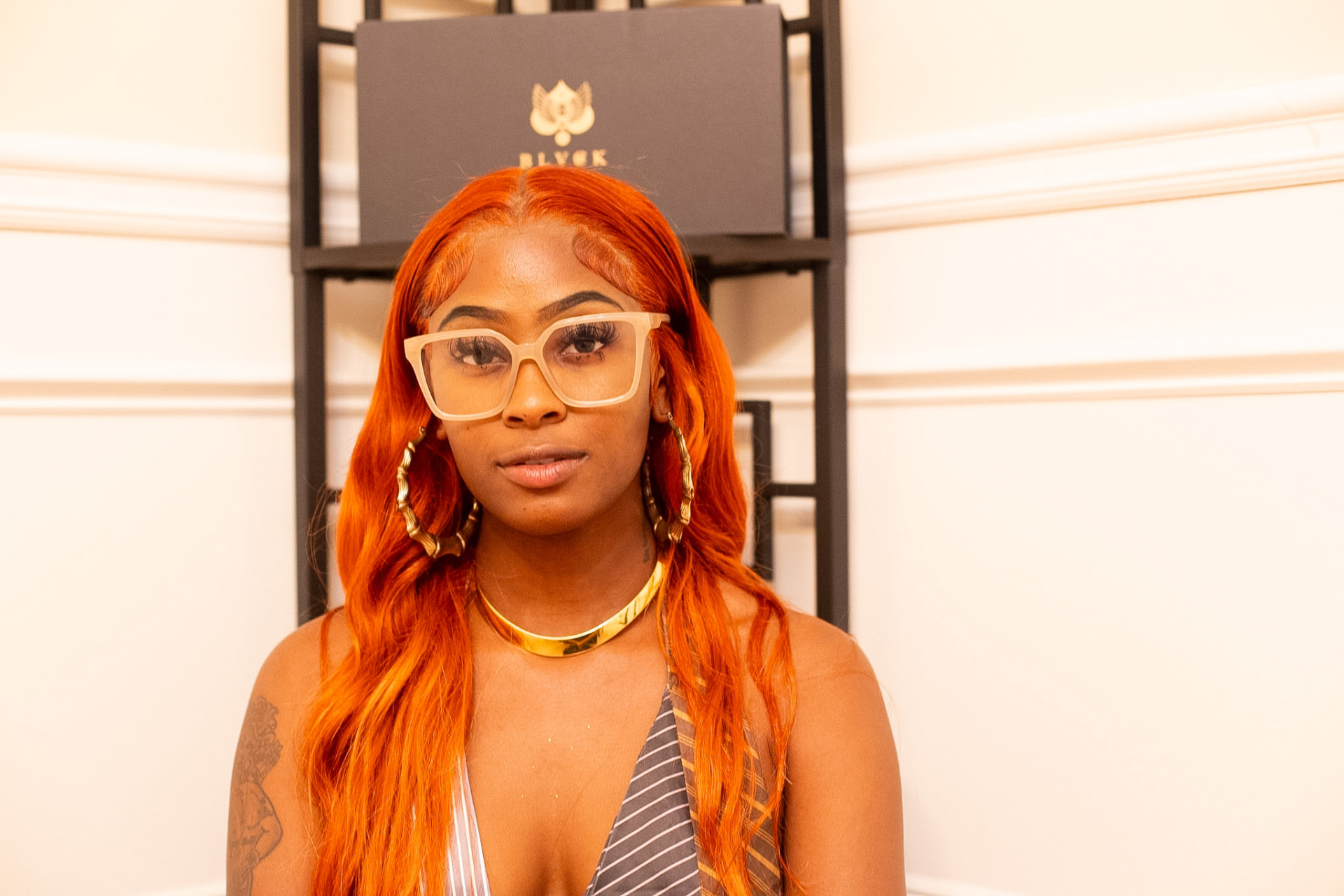 Model portrait — clear frames and gold chain at the BLYSK showcase