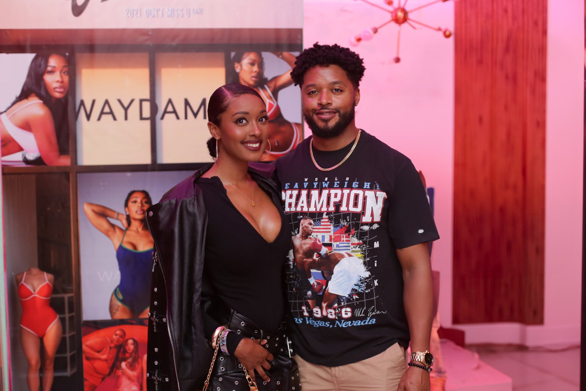 Event couple — leather jacket and vintage tee at a pink-lit venue